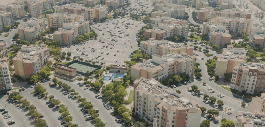 Modern Dubai apartment complex with parking, green spaces, and recreational facilities, featuring Zingo Smart Stay.